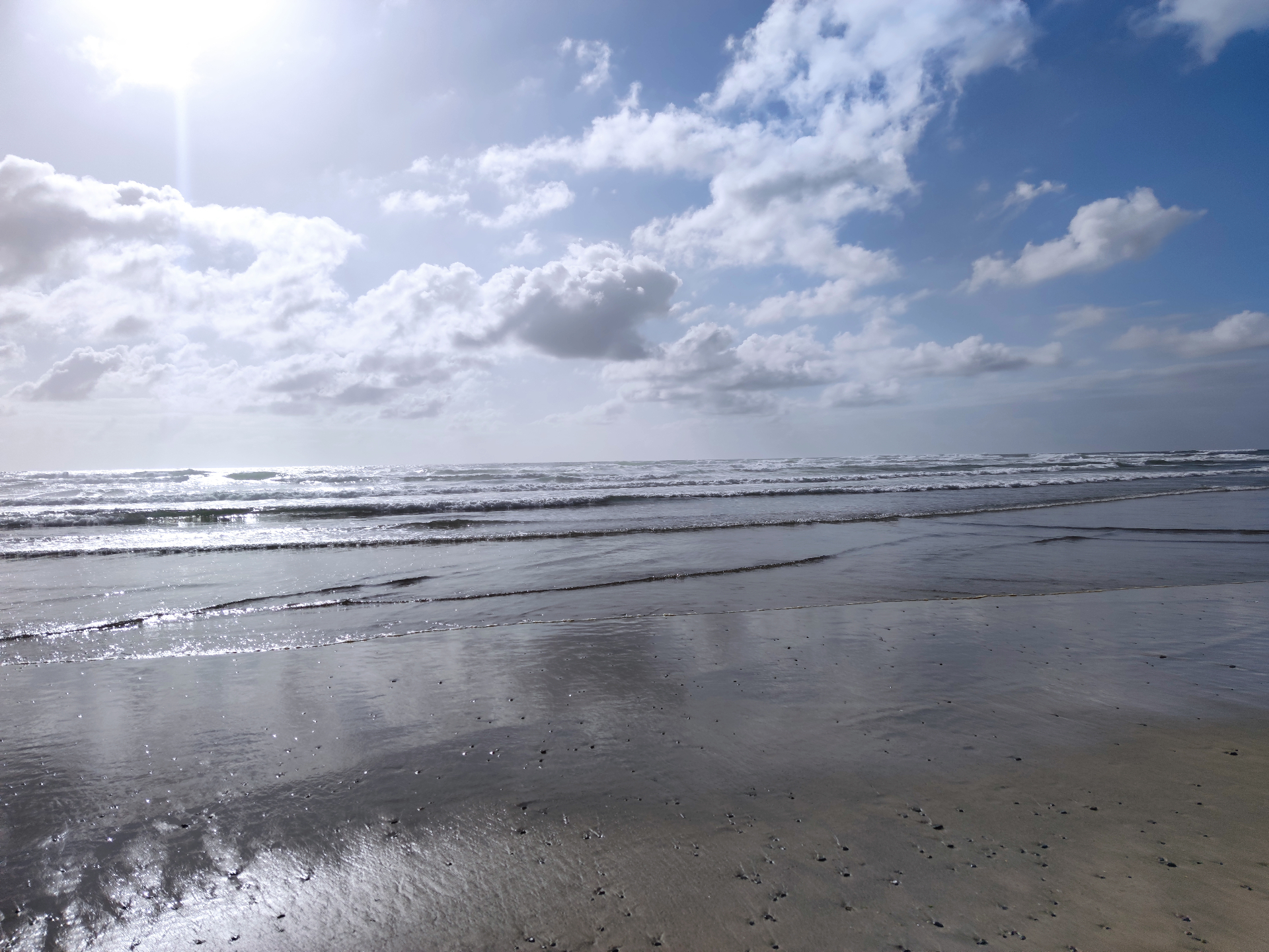 Weiter Sandstrand mit glitzerndem Meer und Wolkenhimmel – Sinnbild für Weite und Ruhe in der therapeutischen Begleitung